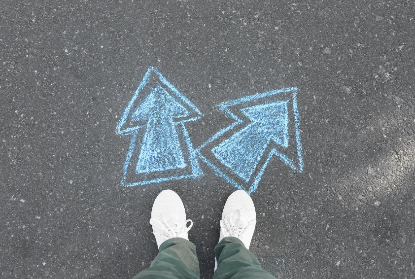 person standing before two arrows drawn in chalk on the ground